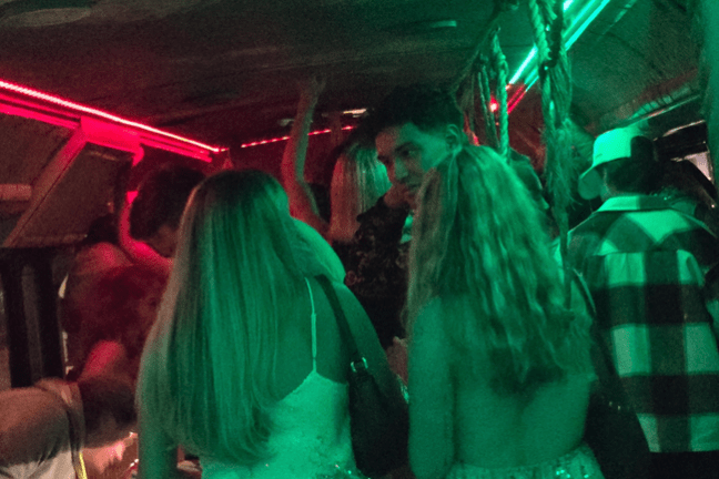 People dancing in a party bus with colorful lights